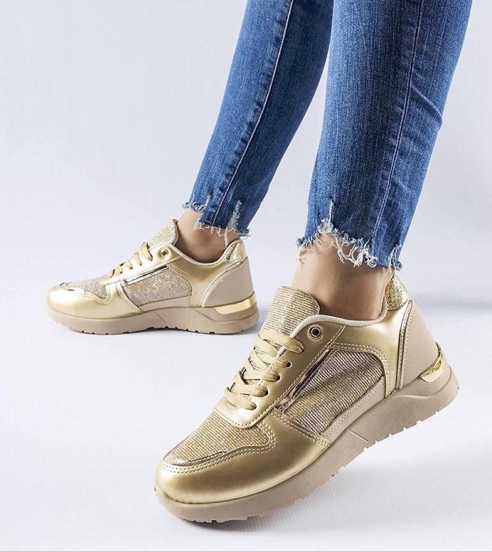 Gold sneakers paired with distressed denim jeans, featuring a mesh upper and metallic finish, ideal for a stylish, modern look.