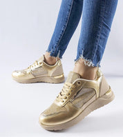 Gold sneakers paired with distressed denim jeans, featuring a mesh upper and metallic finish, ideal for a stylish, modern look.