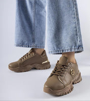 Woman wearing Arpaia Chunky Brown Sneakers with denim jeans, featuring a bold design, eco leather, and a thick rubber sole.