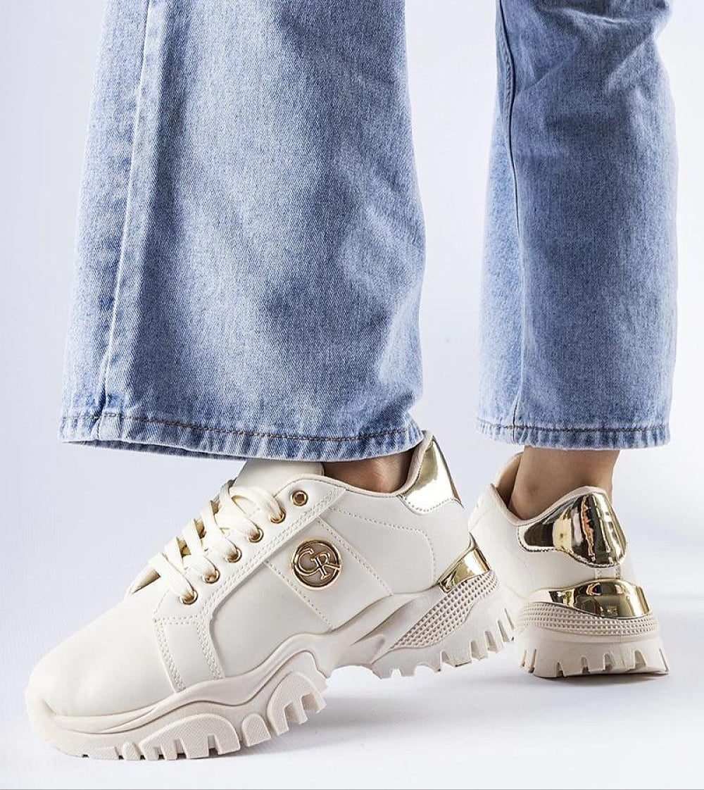 Stylish chunky brown sneakers with gold accents paired with blue jeans, highlighting a modern urban look for women.
