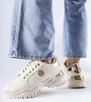 Stylish chunky brown sneakers with gold accents paired with blue jeans, highlighting a modern urban look for women.