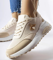 Beige sneakers with bee decoration and chunky sole, worn with distressed jeans.