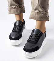 Person wearing black sneakers with a white sole walking on a white background.