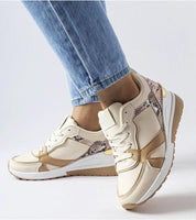 Person wearing beige lace-up wedge sneakers with jeans, featuring eco-friendly faux suede and a 5.5 cm wedge sole for style and comfort.