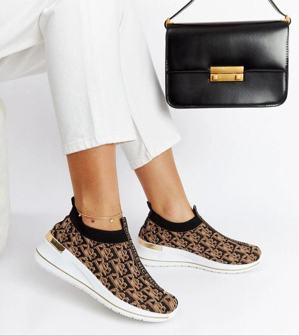 Marronza slip-on wedge sneakers with black-brown textile upper and two-tone rubber sole paired with stylish black handbag.