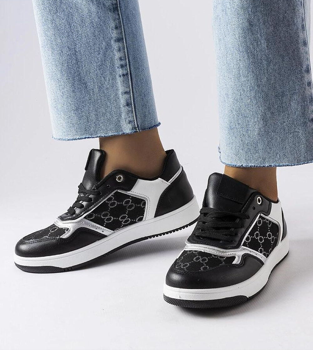 Black and white monogram lace-up sneakers in casual style, worn with light blue jeans, showcasing durable and contemporary fashion.
