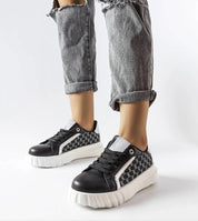 Person wearing Varello Urban Platform Sneakers in Black with eco-friendly synthetic leather and white rubber sole.