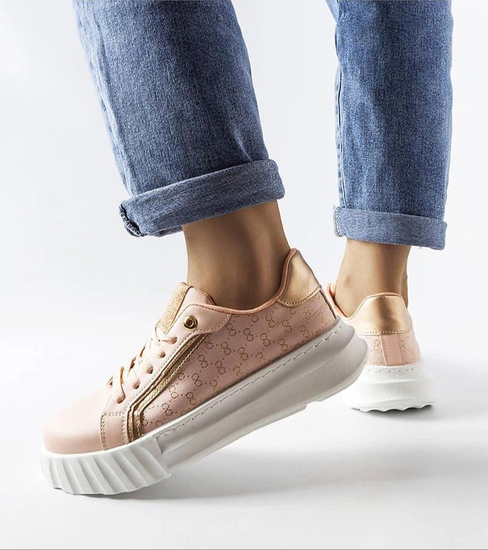 Woman in jeans wearing stylish platform sneakers with a peach color and white sole, highlighting modern streetwear fashion.