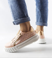 Woman in jeans wearing stylish platform sneakers with a peach color and white sole, highlighting modern streetwear fashion.