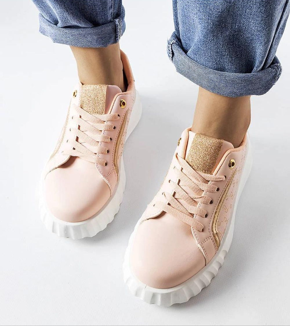 Person wearing pink lace-up sneakers with white soles, styled with rolled-up jeans, showcasing casual streetwear fashion.