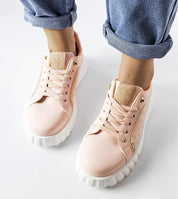 Person wearing pink lace-up sneakers with white soles, styled with rolled-up jeans, showcasing casual streetwear fashion.