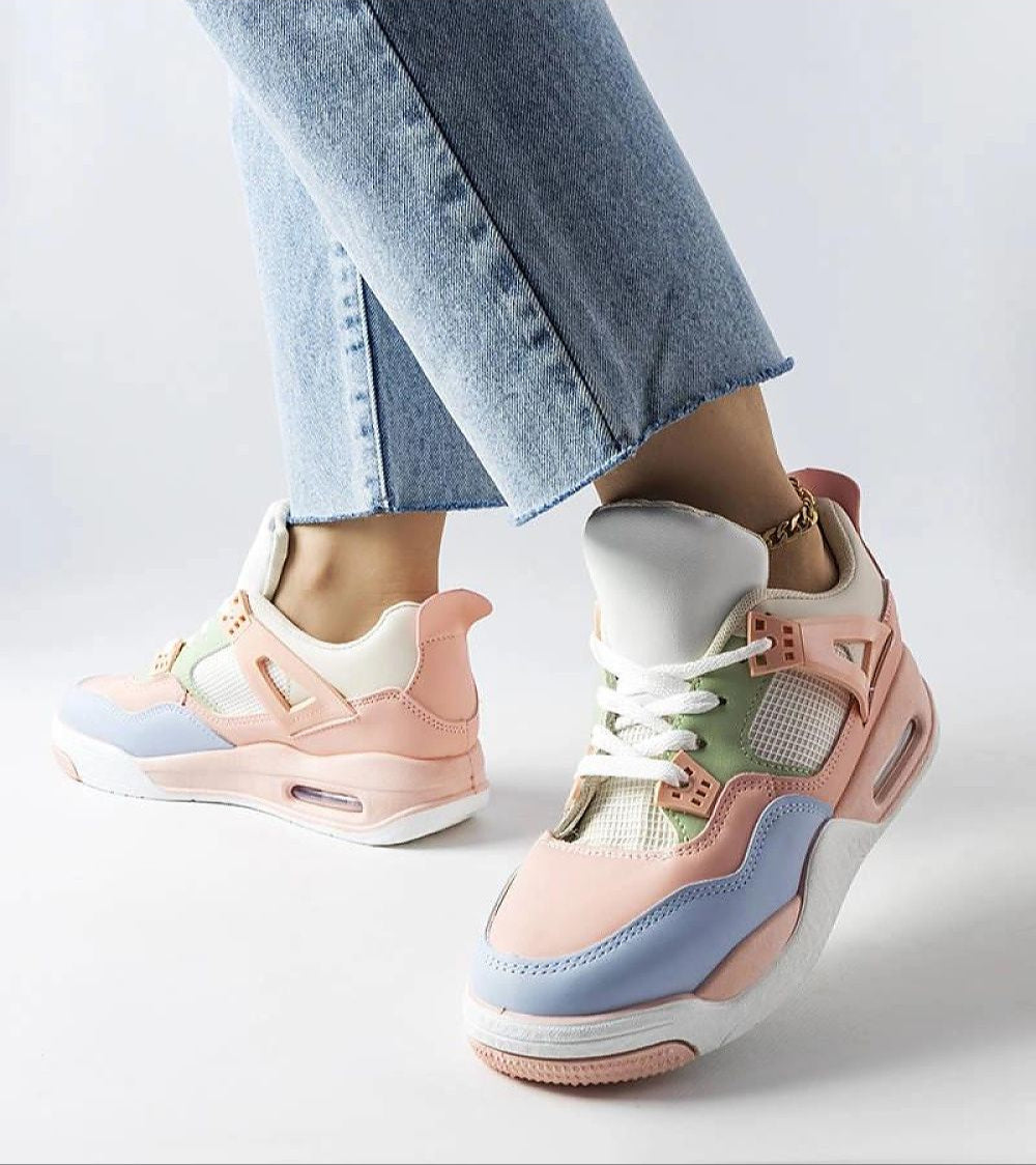 Person wearing pastel-colored sneakers with a mix of pink, blue, and beige, paired with light-wash denim jeans.