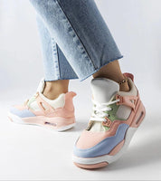 Person wearing pastel-colored sneakers with a mix of pink, blue, and beige, paired with light-wash denim jeans.