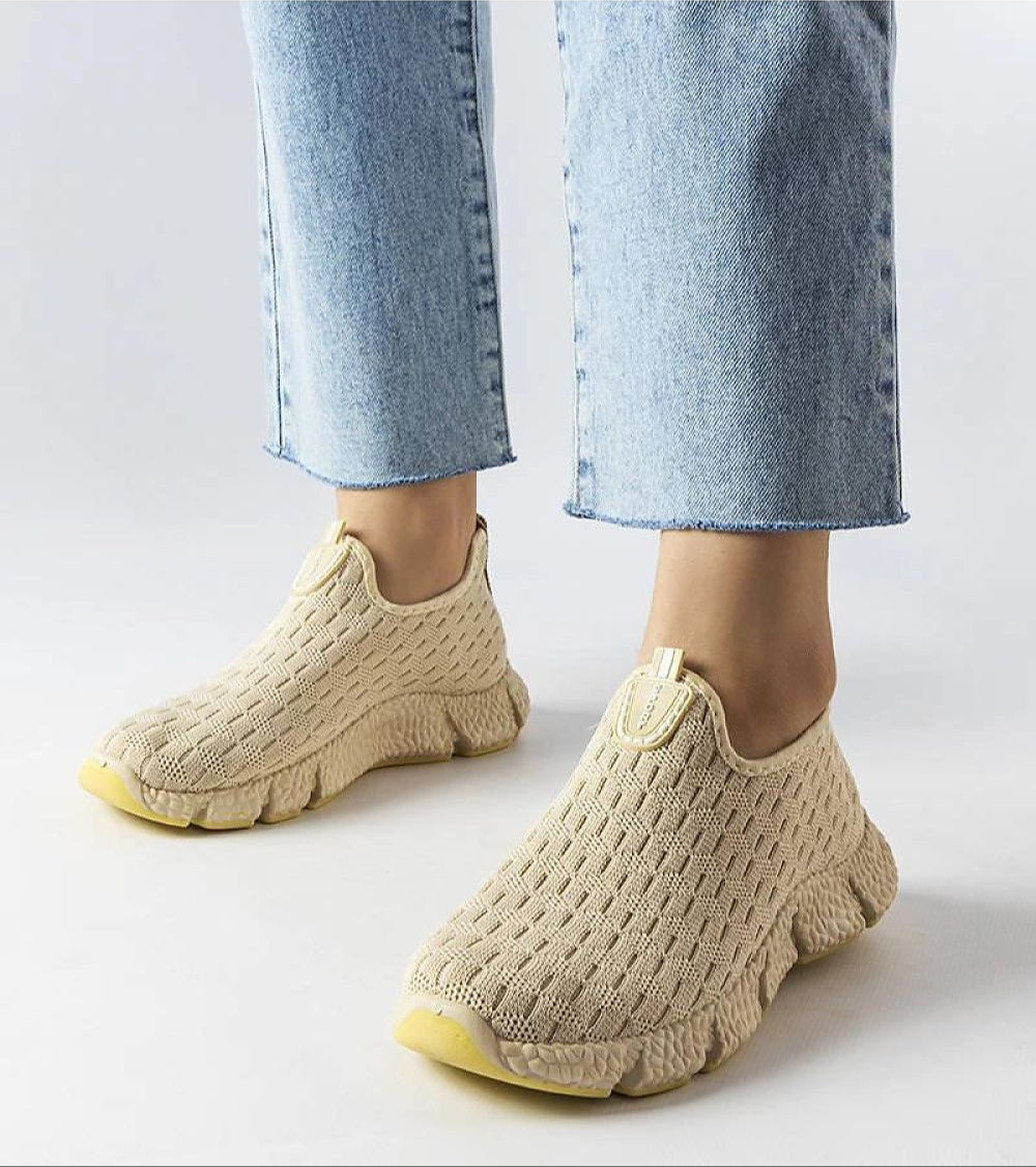 Orellia light beige slip-on sneakers with breathable fabric and beige rubber sole, styled with blue jeans for versatile summer wear.