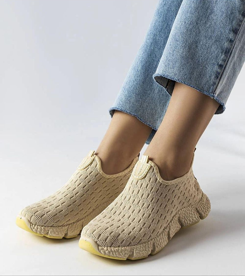 Woman wearing Orellia Light Beige Slip-On Sneakers with blue jeans, showcasing breathable fabric and beige rubber sole for summer wear.