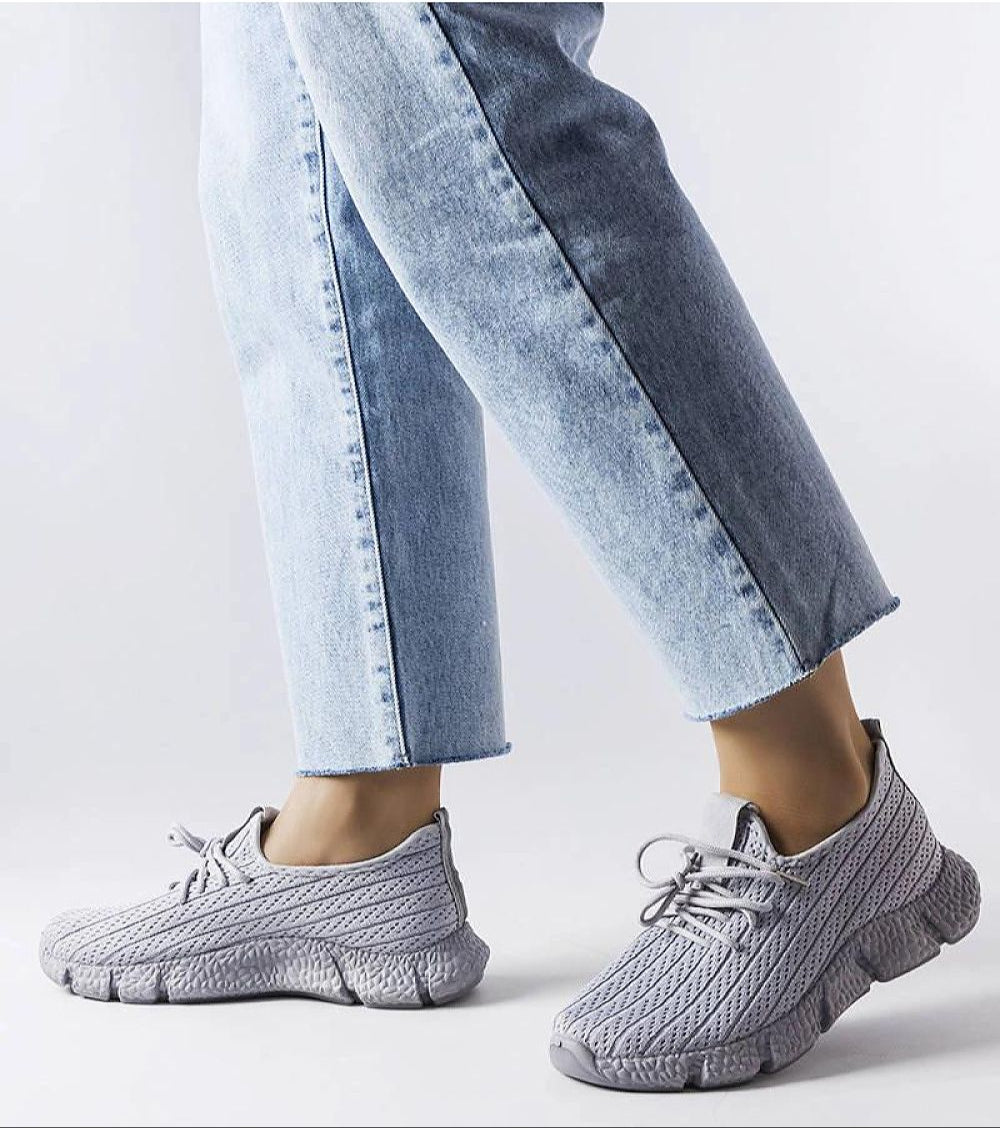 Woman wearing Armonia Gray Summer Sport Sneakers with lace-up front and rubber soles, paired with light denim jeans for casual style.