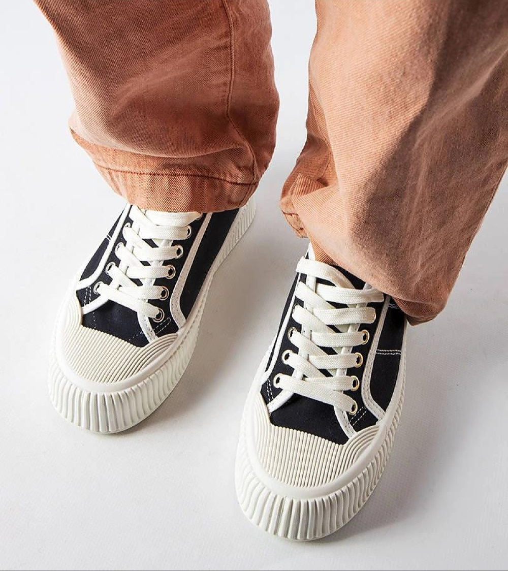 Person wearing Castisca Black Fabric Platform Sneakers with thick white rubber soles and lace-up front, styled with brown pants.