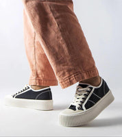 Person wearing Castisca black fabric platform sneakers with thick white soles and lace-up front in casual urban style.