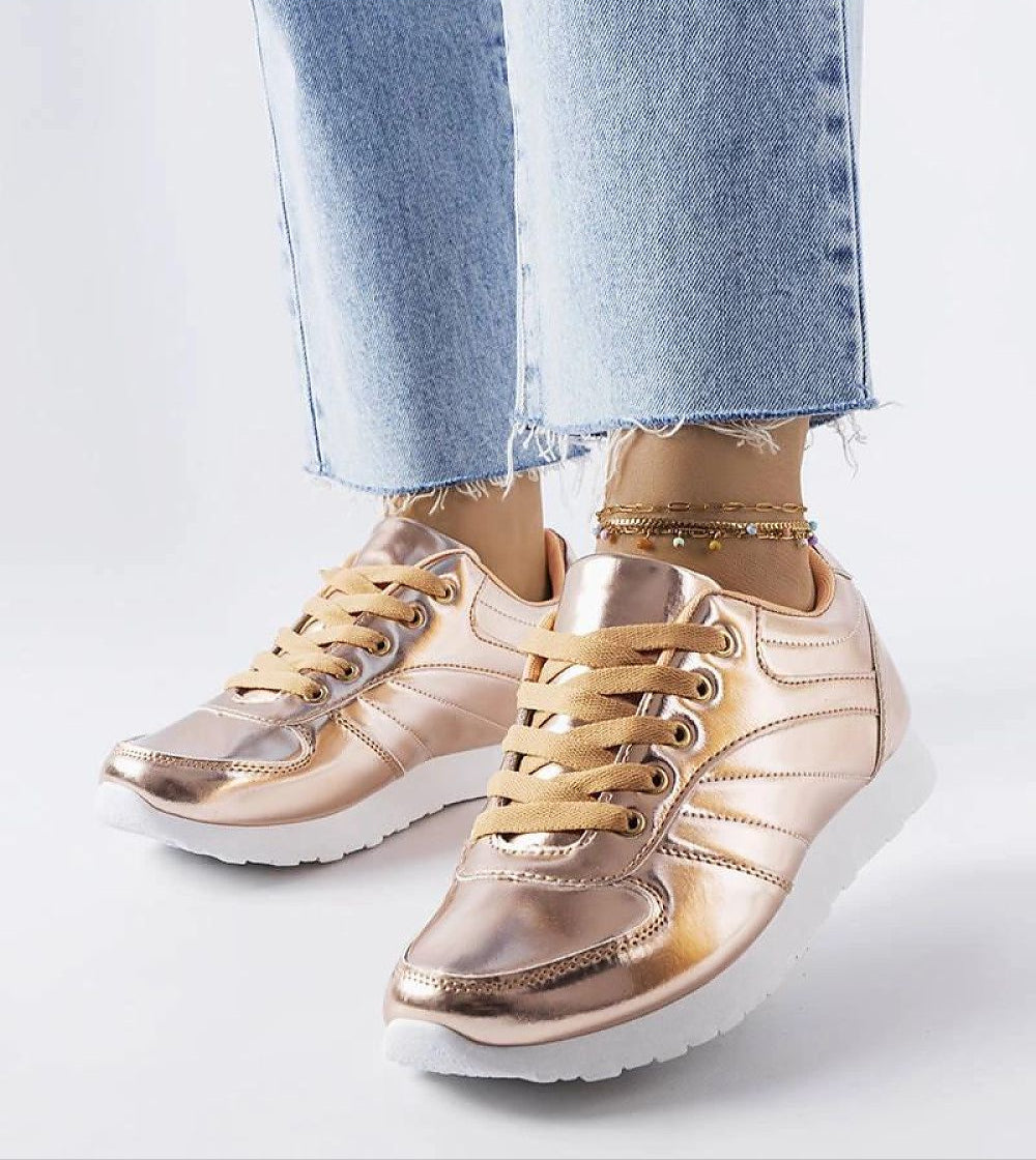 Quirayne golden low-top sneakers with white soles and lace-up closure, paired with casual denim jeans, perfect for sunny days.