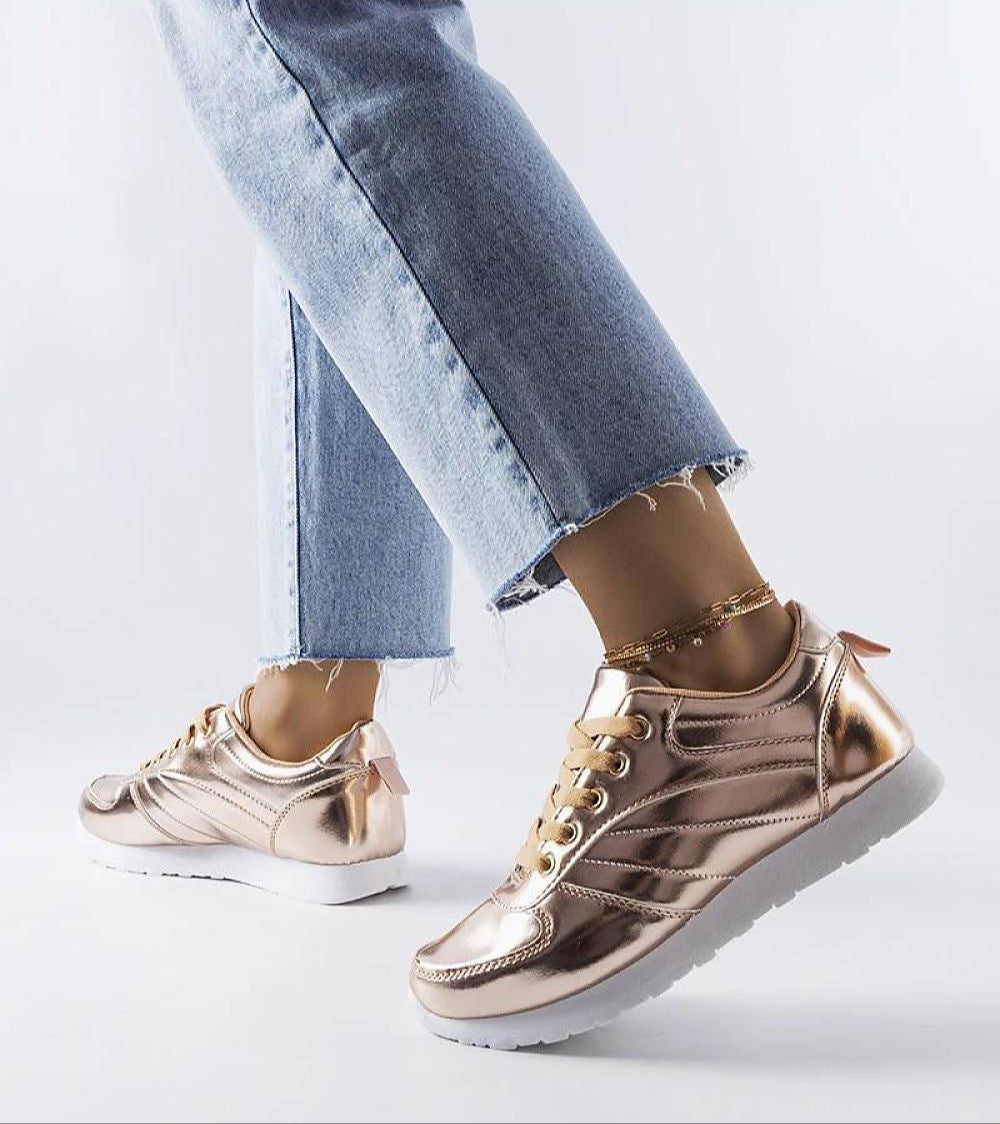 Quirayne Golden Low-Top Sneakers styled with frayed jeans, showcasing faux leather and lace-up design on white rubber sole.