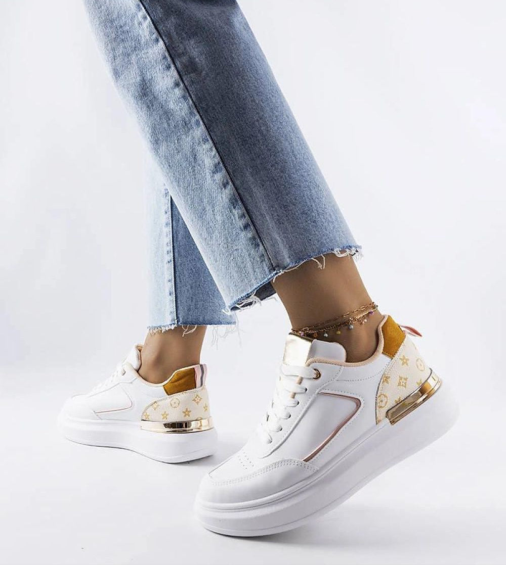 Person wearing Marriale white sneakers with beige detail and blue jeans, featuring a lace-up front and eco leather design.