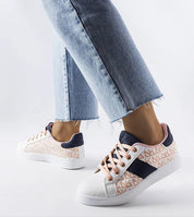 Woman wearing Alelya Doringer StrideGlow Sneakers in white with colorful accents, paired with light blue jeans.