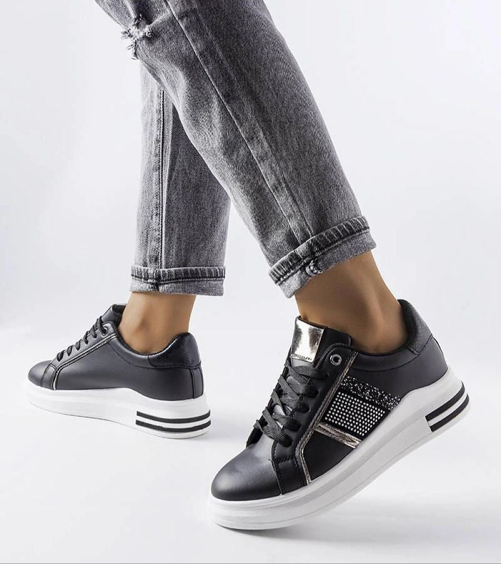 Woman wearing Meralla rhinestone platform sneakers in black and gray jeans, showcasing stylish and sporty design.