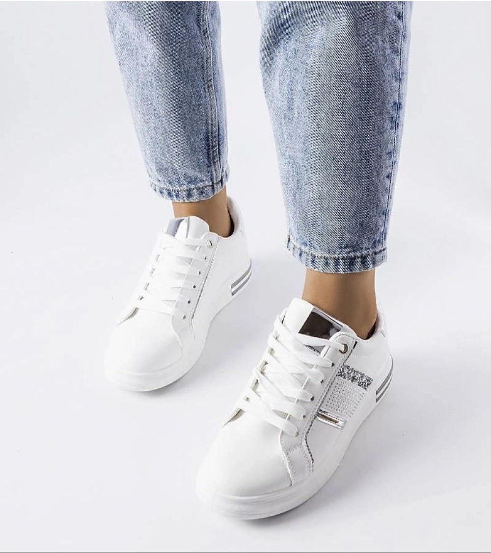 Woman wearing Meralla rhinestone platform sneakers with jeans, showcasing elegant beige design with shimmering rhinestone accents.