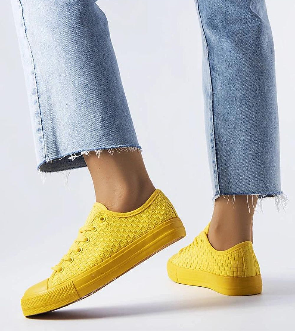 Person wearing yellow Revarya woven lace-up summer sneakers with blue jeans.