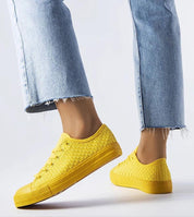 Person wearing yellow Revarya woven lace-up summer sneakers with blue jeans.