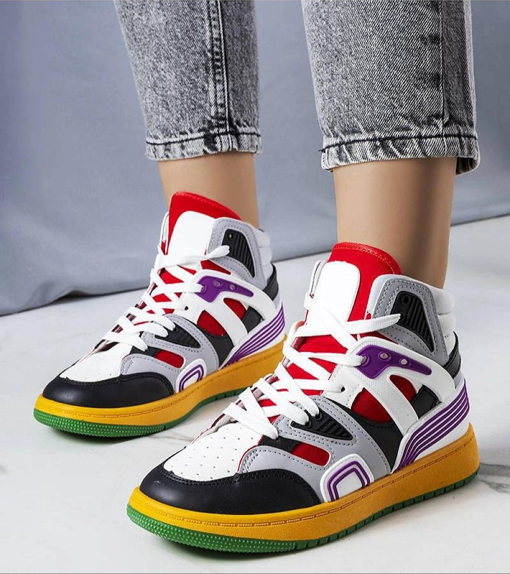 Colorful high-top sneakers with multicolored panels and white laces, worn with rolled-up jeans on a marble floor.