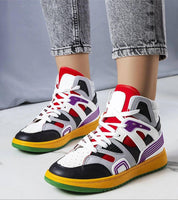 Colorful high-top sneakers with multicolored panels and white laces, worn with rolled-up jeans on a marble floor.