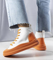 Person wearing Ossavine fabric platform lace sneakers with orange soles and laces, paired with light blue jeans.