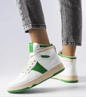 White and green Ormelya high-top sneakers with eco leather upper and lace-up design on person wearing jeans.