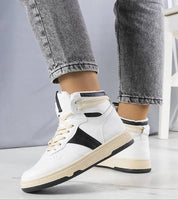 Person wearing Ormelya high-top everyday sneakers in white eco leather with black accents and 3 cm sole, shown with casual jeans.