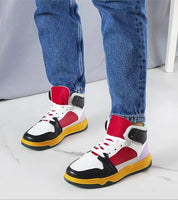 Colorful high-top sneakers with red, black, and white design, featuring yellow soles, worn with blue jeans on a marble floor.