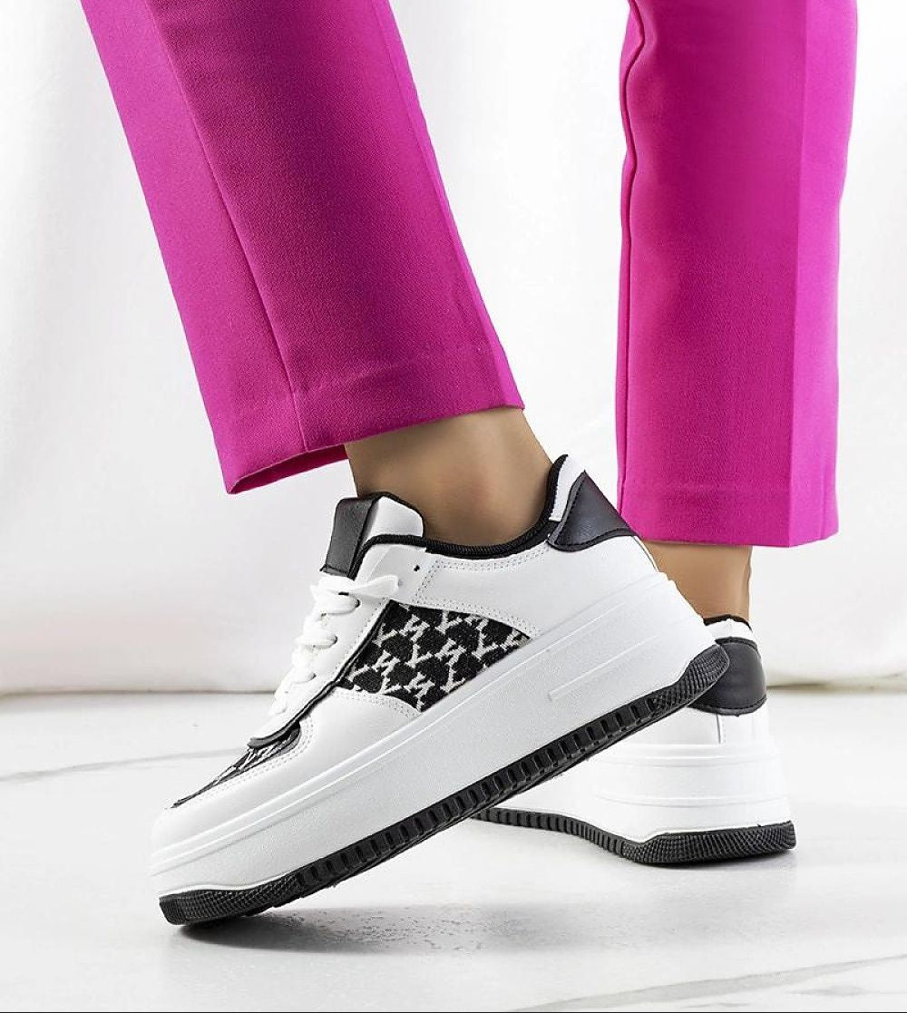 Woman wearing Myrelith Lifted Sole Lace Sneakers with eco leather upper and elevated rubber sole, paired with pink trousers.