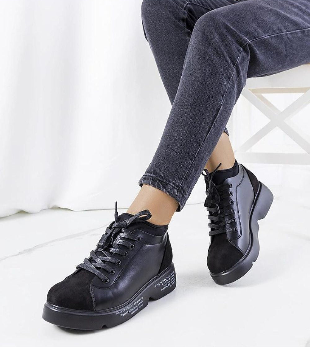 Person wearing Odyrelle Contour Platform Sneakers in black, showcasing minimalist design and structured sole for style and comfort.