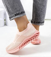 Woman wearing Zavella Slip-On Sport Knit Sneakers in pink, showcasing breathable textile and flexible sole design for summer comfort.