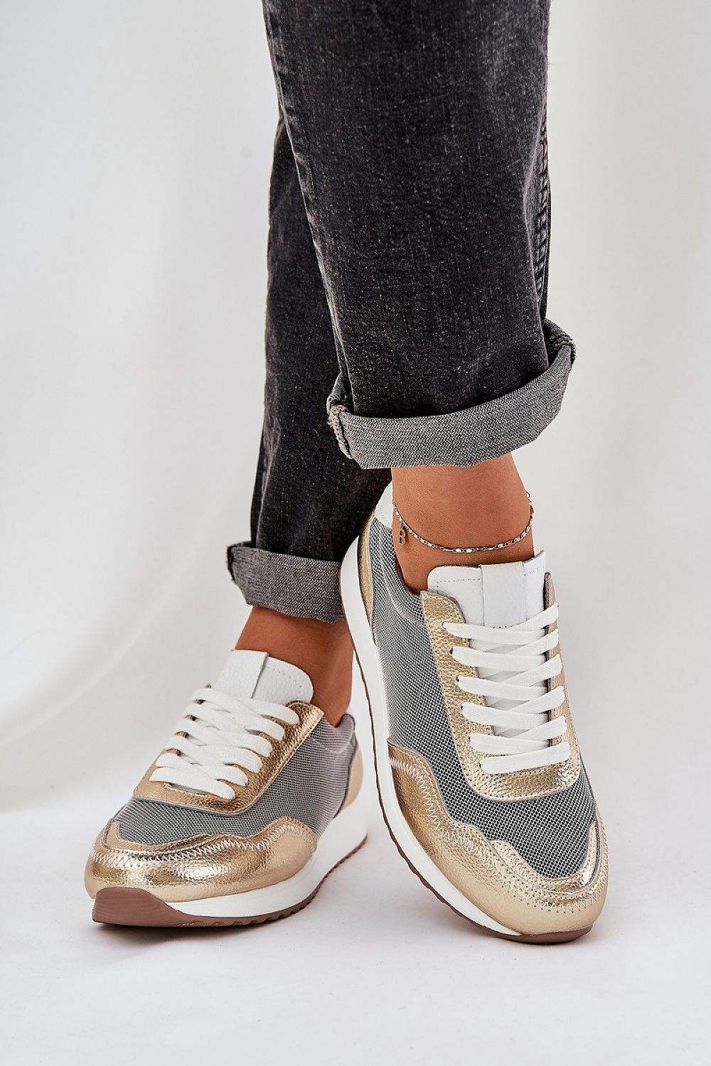 Person wearing Eryndel ActiveFit Leather Sport Shoes in gold and grey, showing lace-up design and flexible fit on rolled-up jeans.