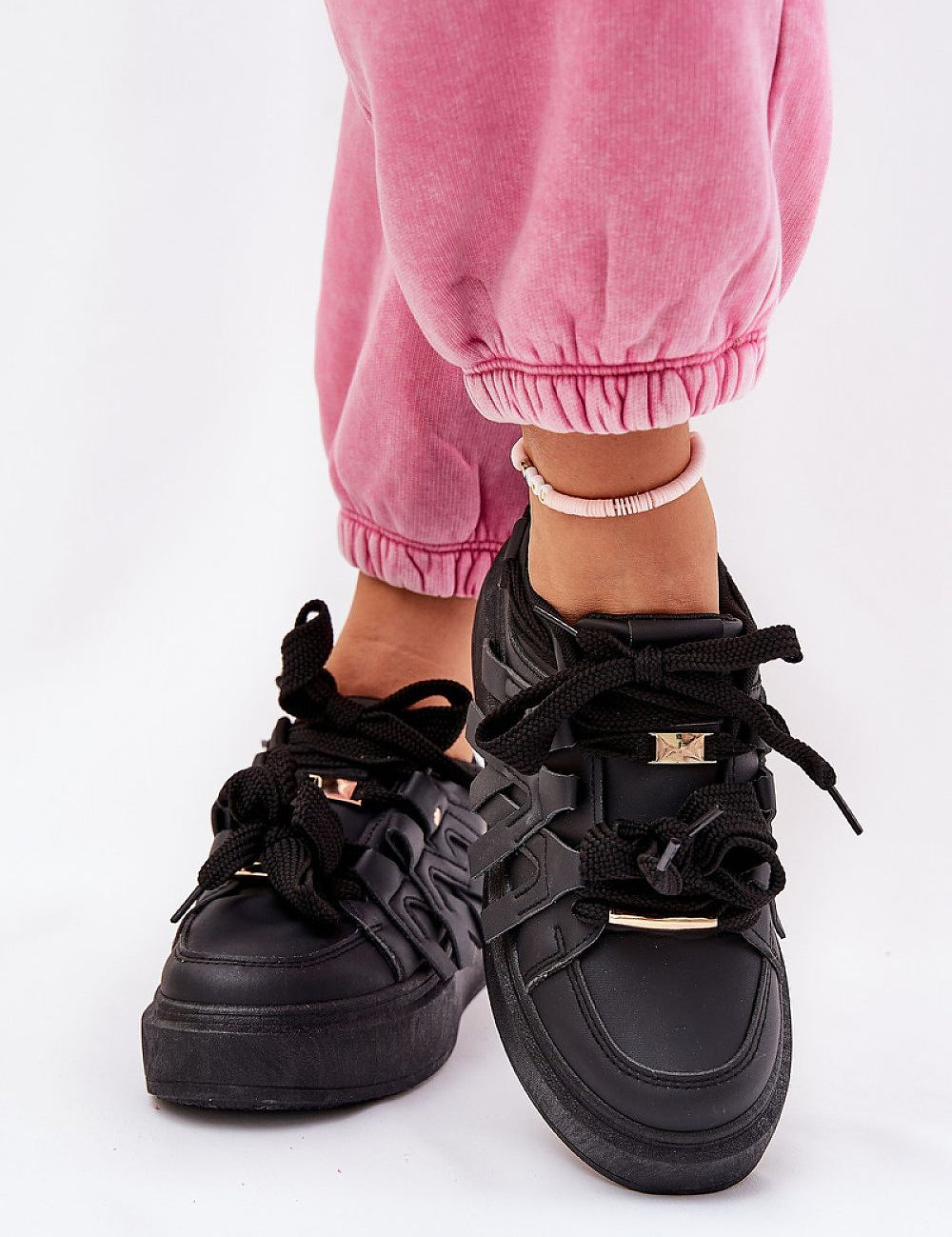 Person wearing Cernia Synthetic Platform Lace Sneakers in black with pink pants, showcasing contemporary streetwear style and comfort.