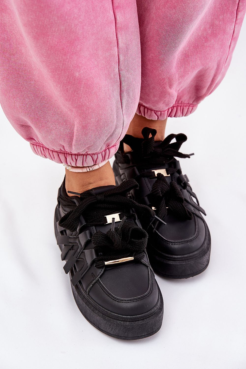 Person wearing Cernia Synthetic Platform Lace Sneakers in black with pink pants, highlighting the structured design and platform sole.