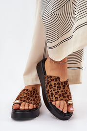 Woman wearing leopard print sandals with black platform, paired with patterned wide-leg pants, showcasing fashion-forward style.
