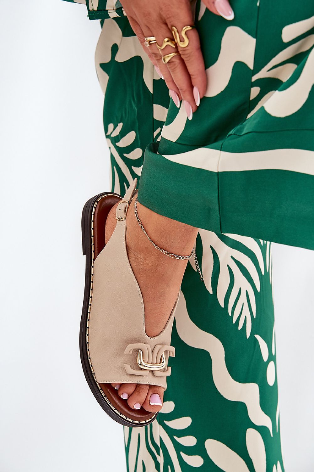 Almira Flat Eco-Leather Sandals with decorative front detail, worn with green patterned trousers. Ideal for elegant summer wear.