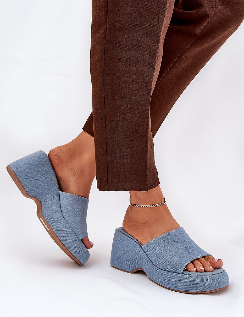 Woman wearing Zalhera Elevated Textile Wedge Sandals in blue with open-toe design and high platform, paired with brown pants.
