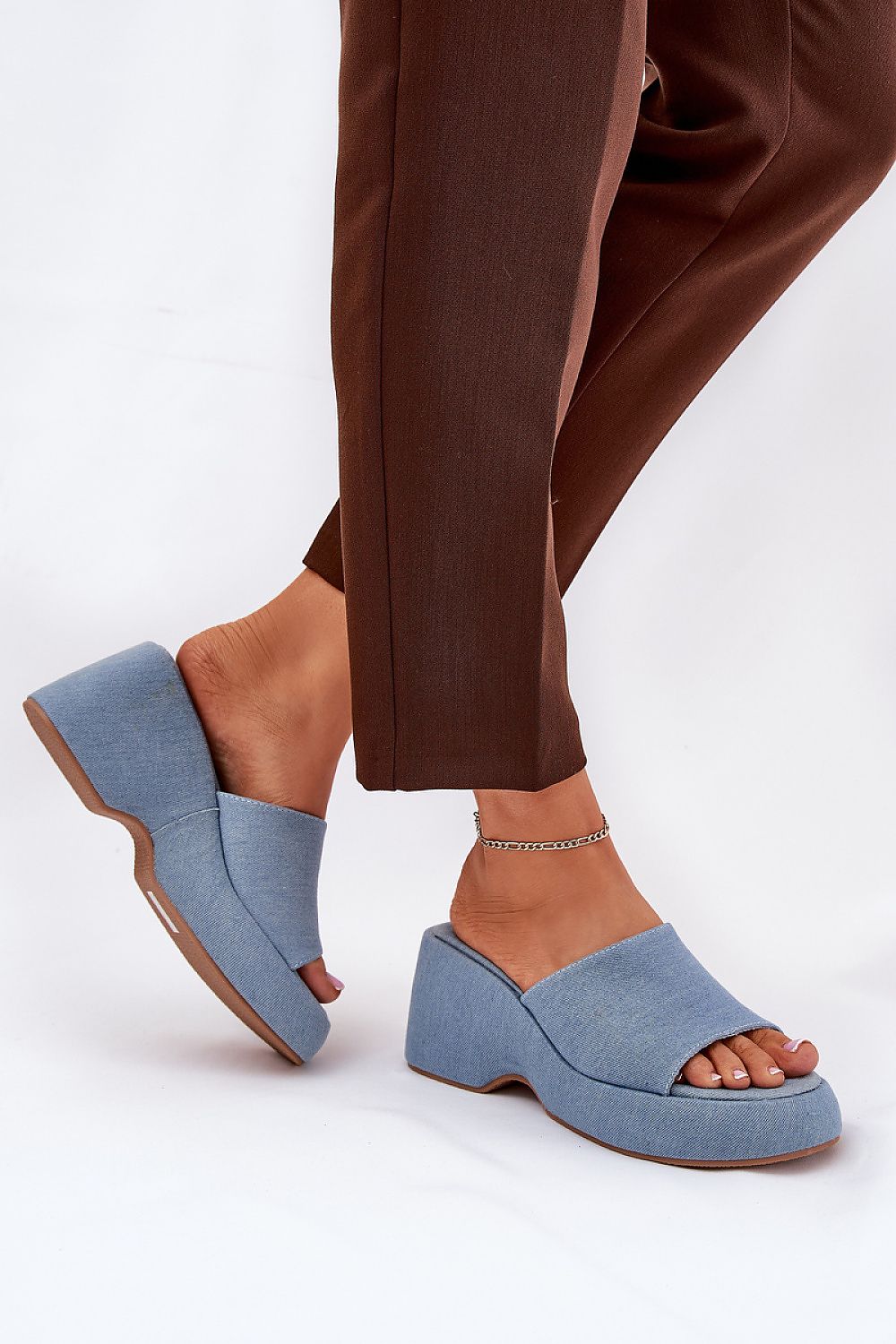 Woman wearing Zalhera Elevated Textile Wedge Sandals in blue with open-toe design and high platform, paired with brown pants.