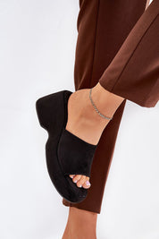 Woman wearing Zalhera Elevated Textile Wedge Sandals, suede-like black open-toe design, paired with brown pants for a chic look.