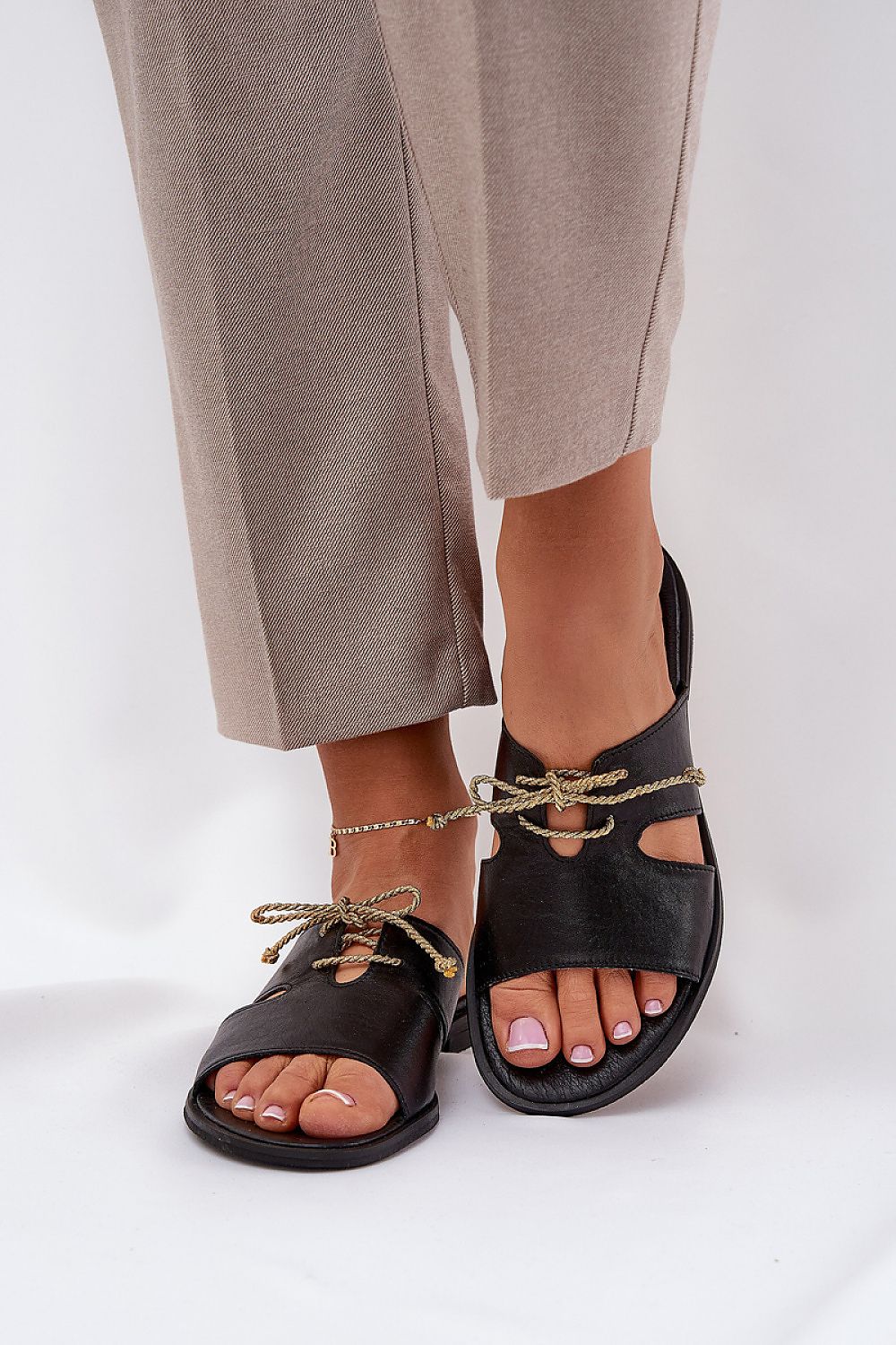 Alvessa Gold Accent Leather Slides with delicate golden string detail and minimalist design, worn with beige trousers.