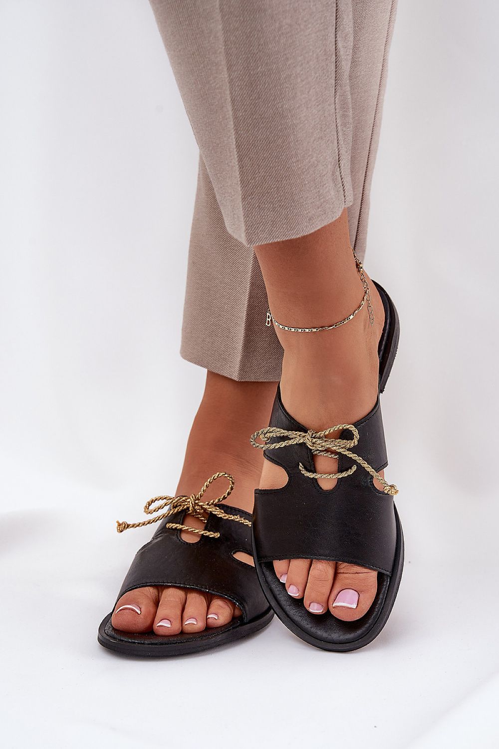 Woman wearing Alvessa Gold Accent Leather Slides with golden string detail and black leather for a stylish summer look