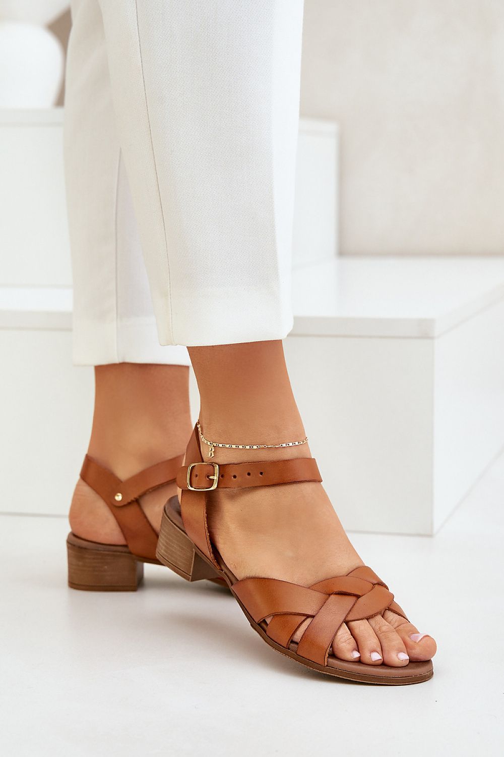 Woman wearing Valerinne Cross-Strap Leather Sandals with block heel, featuring adjustable ankle closure and natural leather upper.